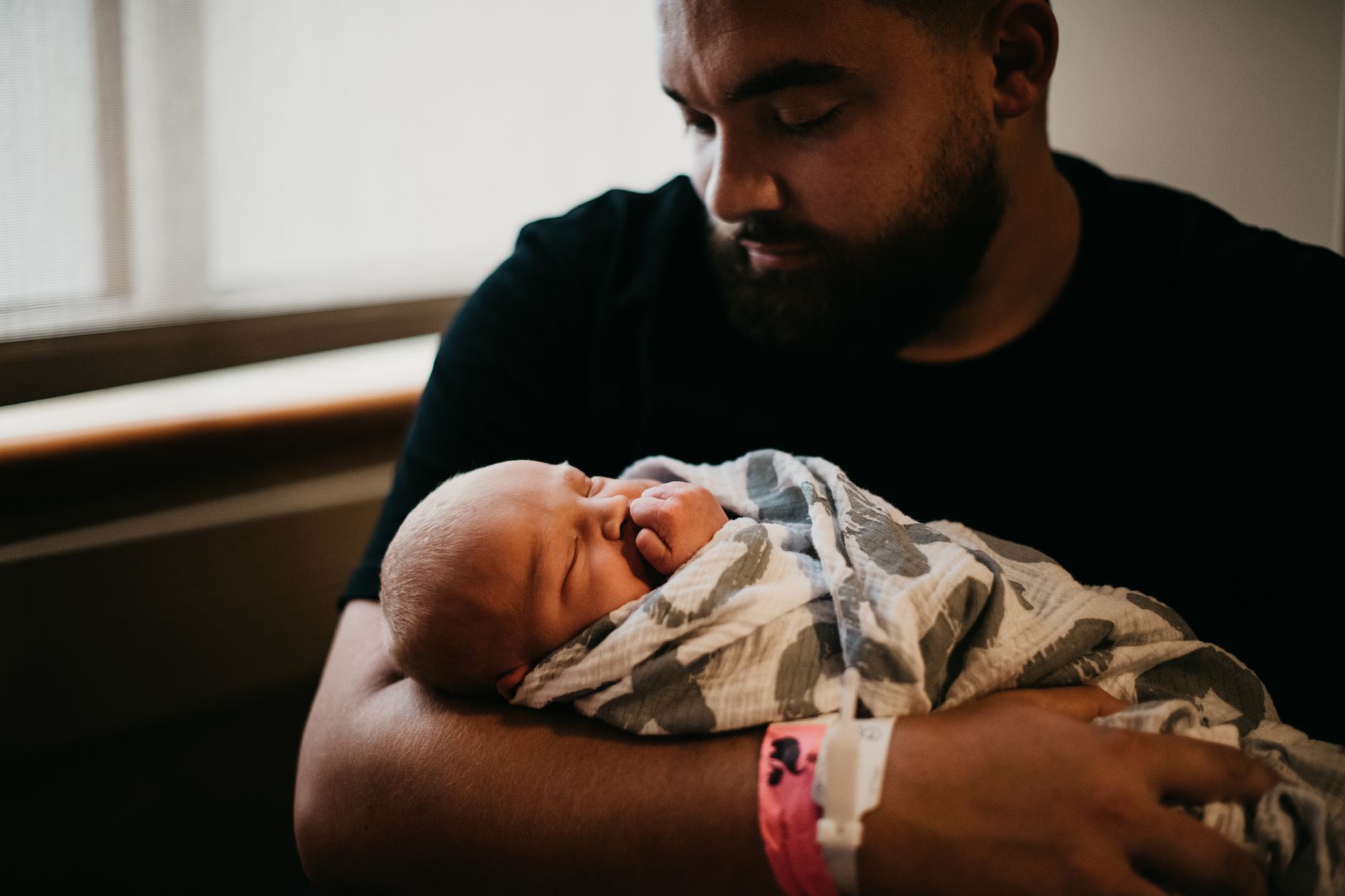 Ilustrasi: A tender moment of a father holding his newborn baby wrapped in a blanket indoors.