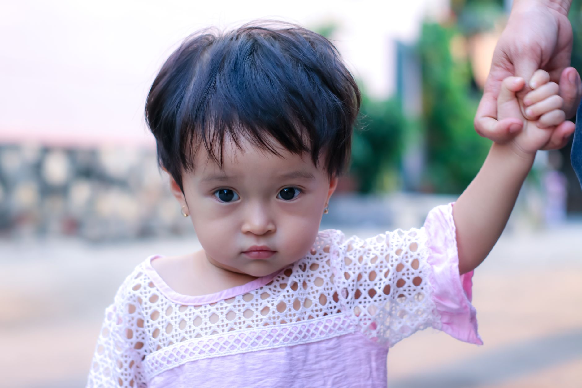 Ilustrasi: Heartwarming portrait of a cute toddler girl holding an adult's hand outside.