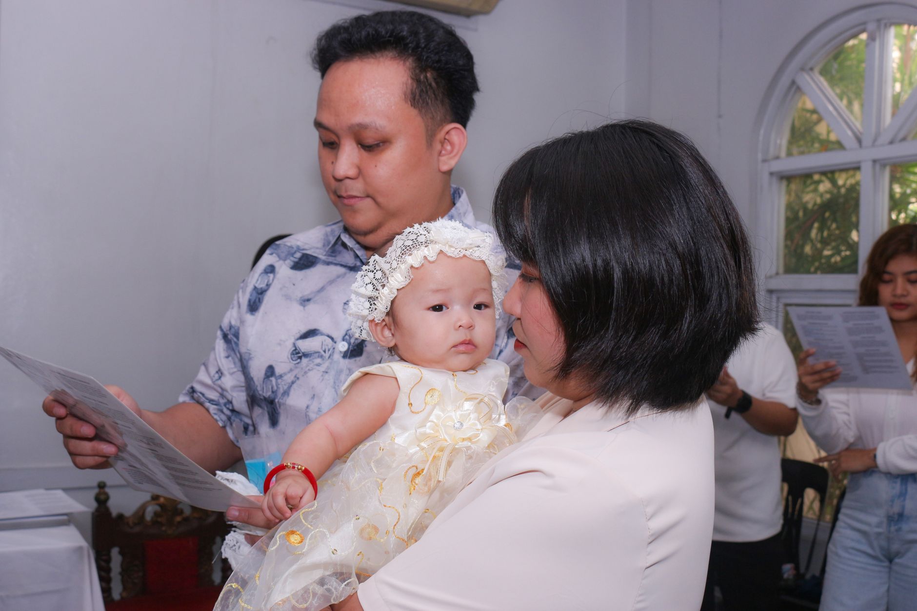 Ilustrasi: Asian parents with baby during a religious ceremony inside a church.