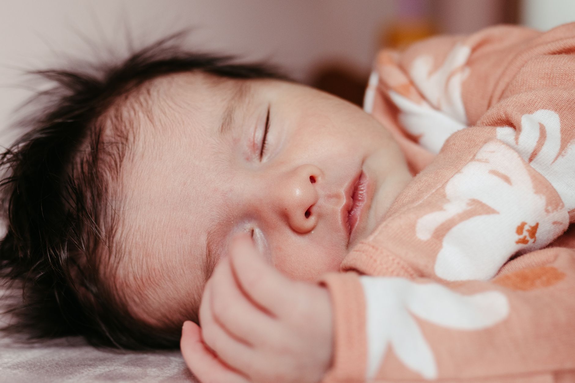 Ilustrasi: Close-up of a newborn baby peacefully sleeping in a cozy outfit, exuding innocence and tranquility.