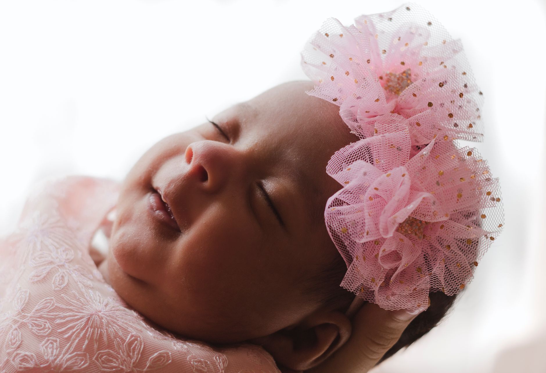 Ilustrasi: Close-up portrait of a peaceful baby sleeping with a pink floral headband.