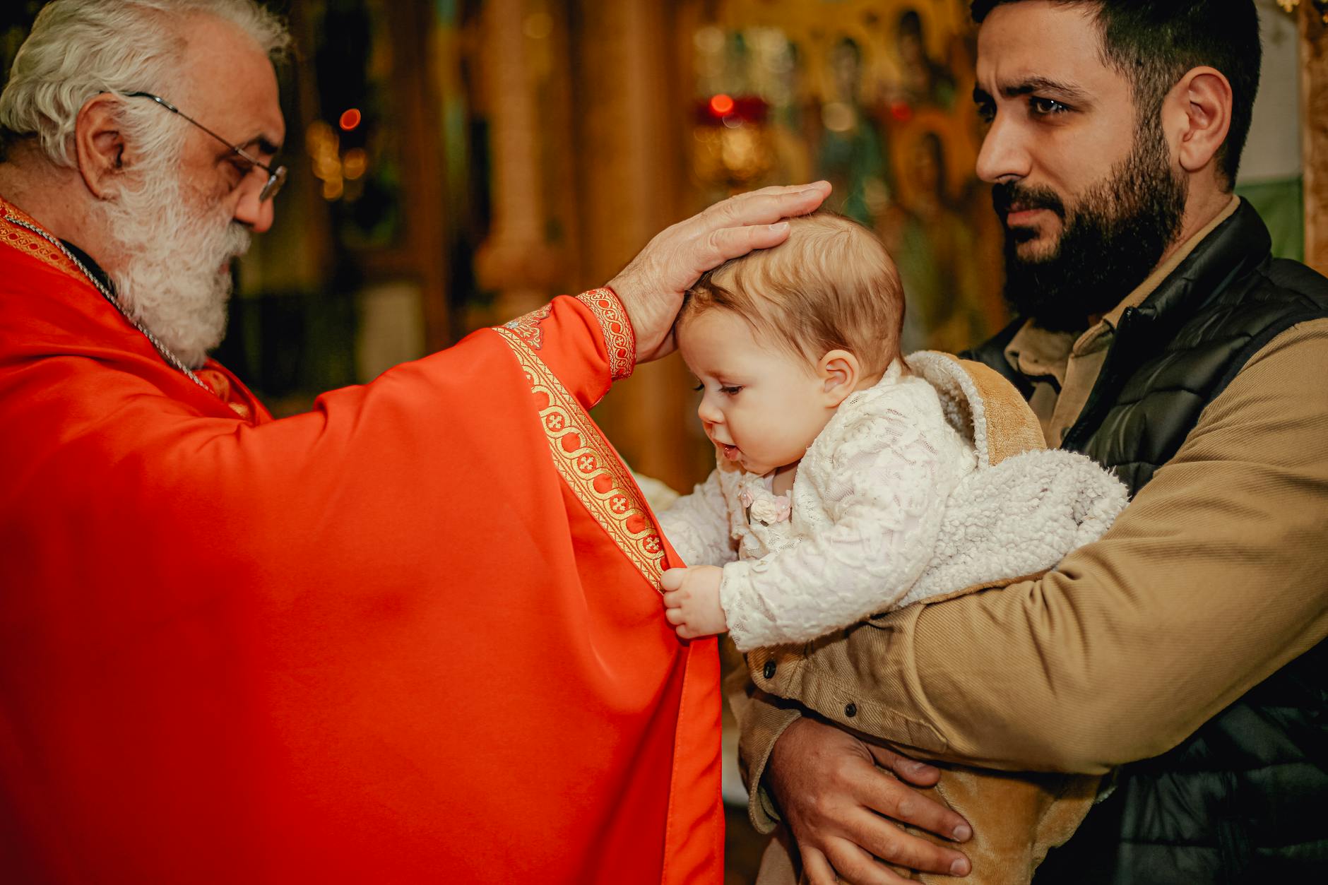 Ilustrasi: A priest performs a blessing on a child held by a man inside a church.