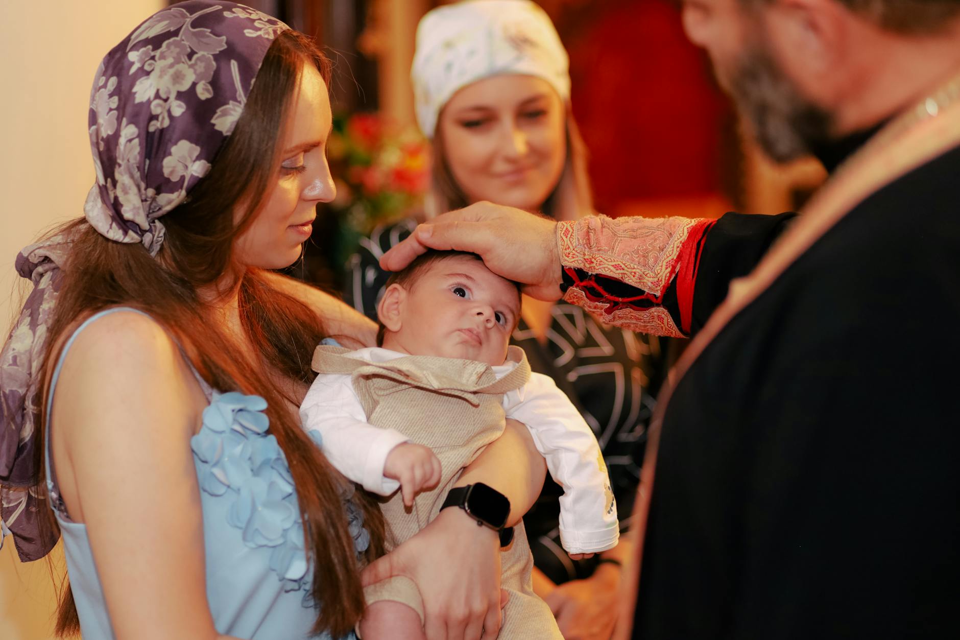 Ilustrasi: A baby being baptized by a priest, surrounded by family during a traditional ceremony indoors.