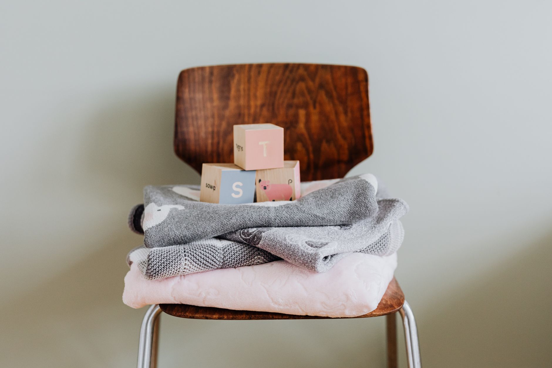 Ilustrasi: Wooden blocks and cozy baby blankets on a modern chair, ideal for nursery decor.