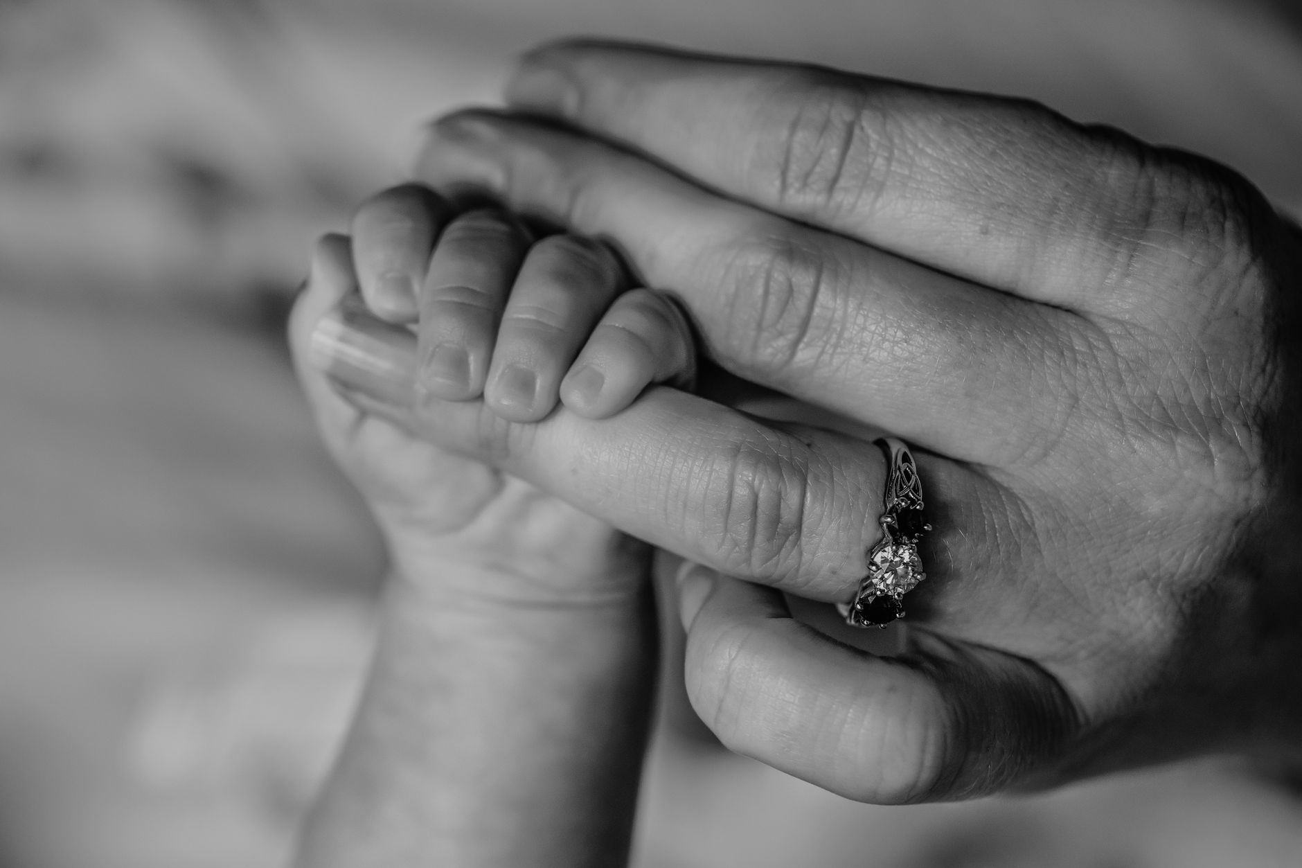 Ilustrasi: Close-up black and white photo of baby hand holding mother's finger with love.