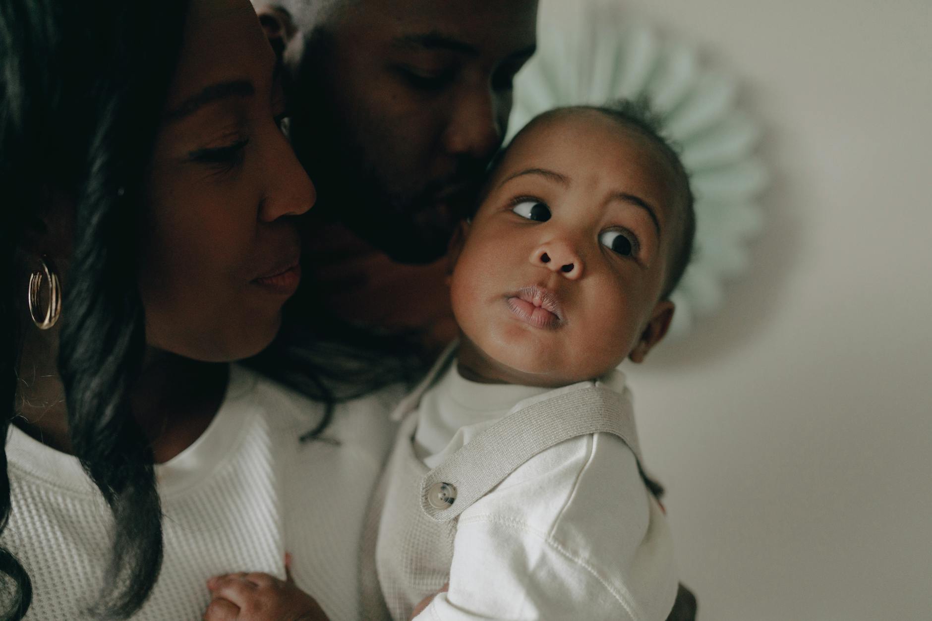 Ilustrasi: Close-up of a joyful African American family sharing a tender moment with their baby.