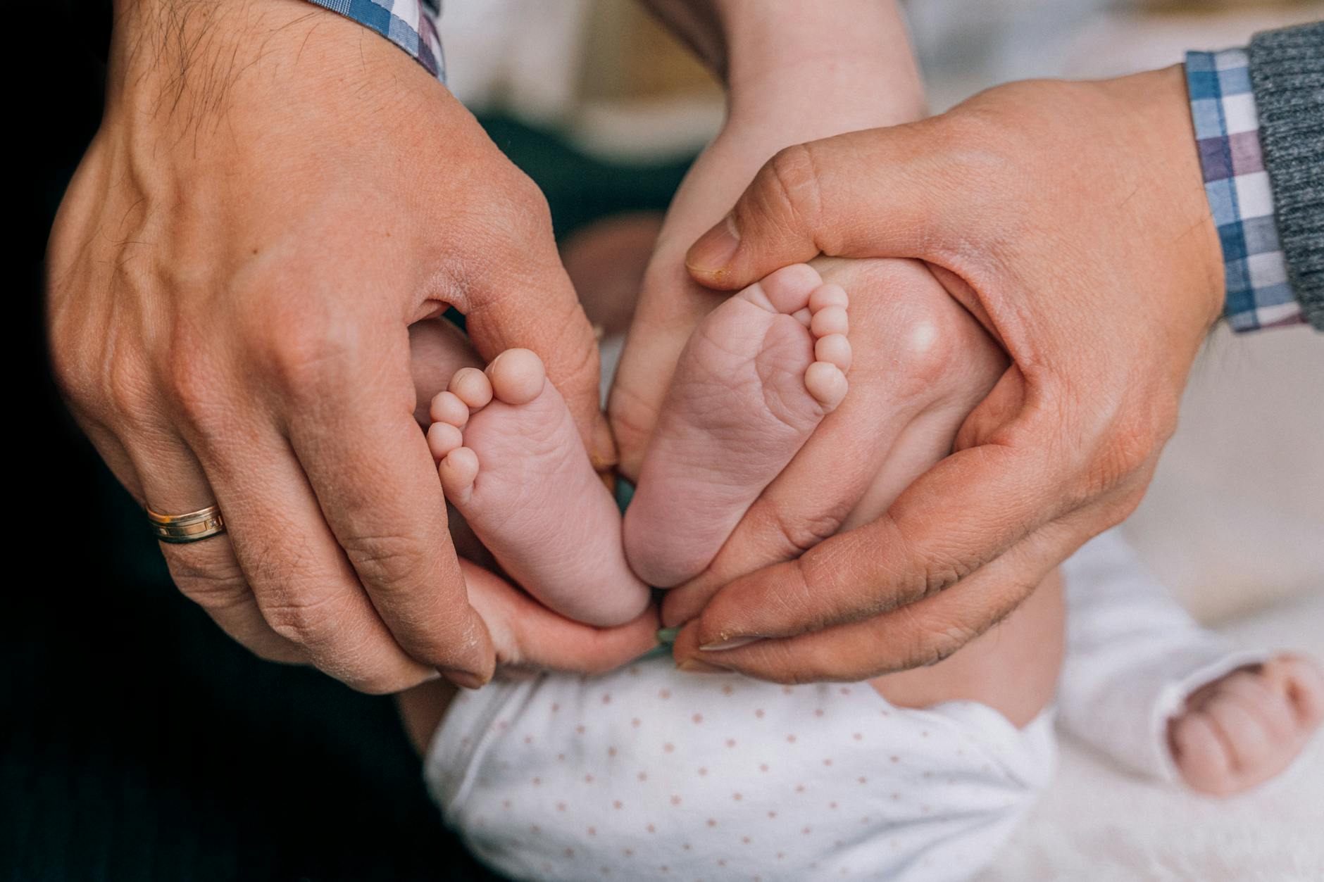 Ilustrasi: Close-up of a parent's hands gently holding baby feet, symbolizing love and care.