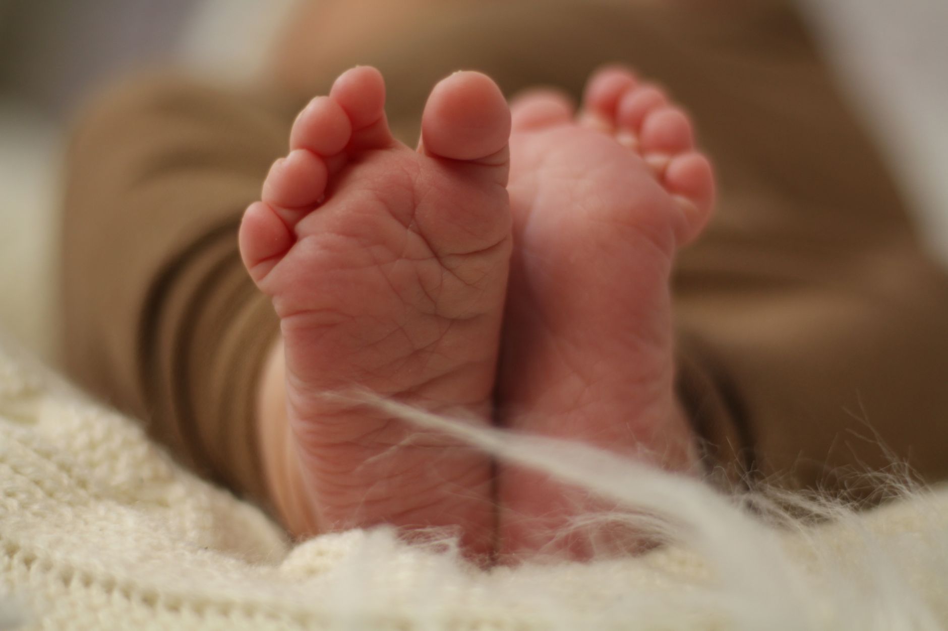 Ilustrasi: Tender close-up photo of a newborn baby's tiny feet resting on a soft blanket.
