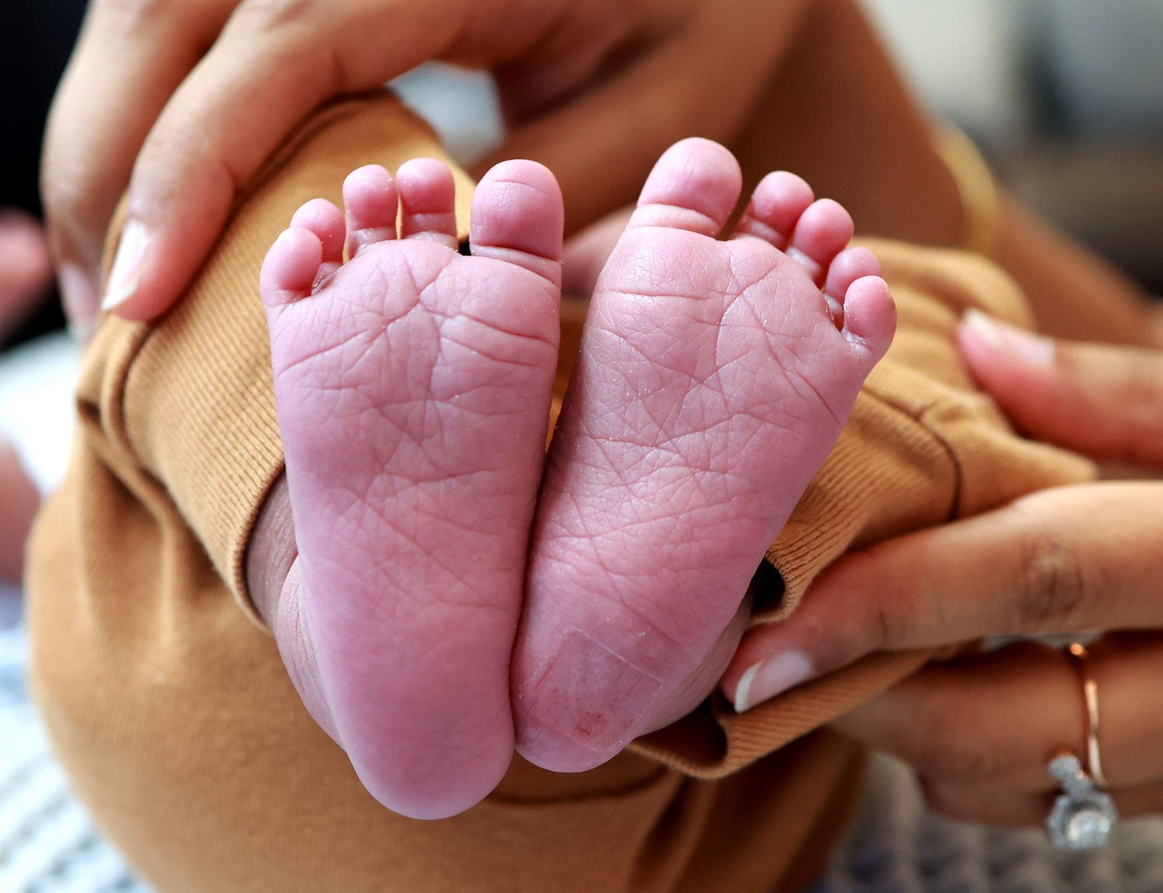 Ilustrasi: Tender close-up of a baby's feet cradled in a parent's hands, expressing love and care.