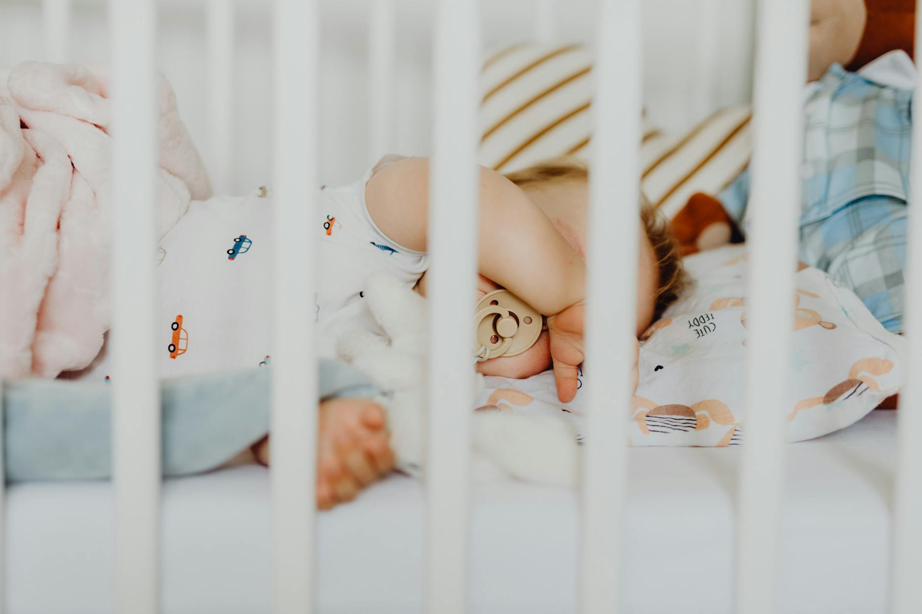 Ilustrasi: A baby peacefully sleeping with a pacifier in a cozy crib with plush blankets.