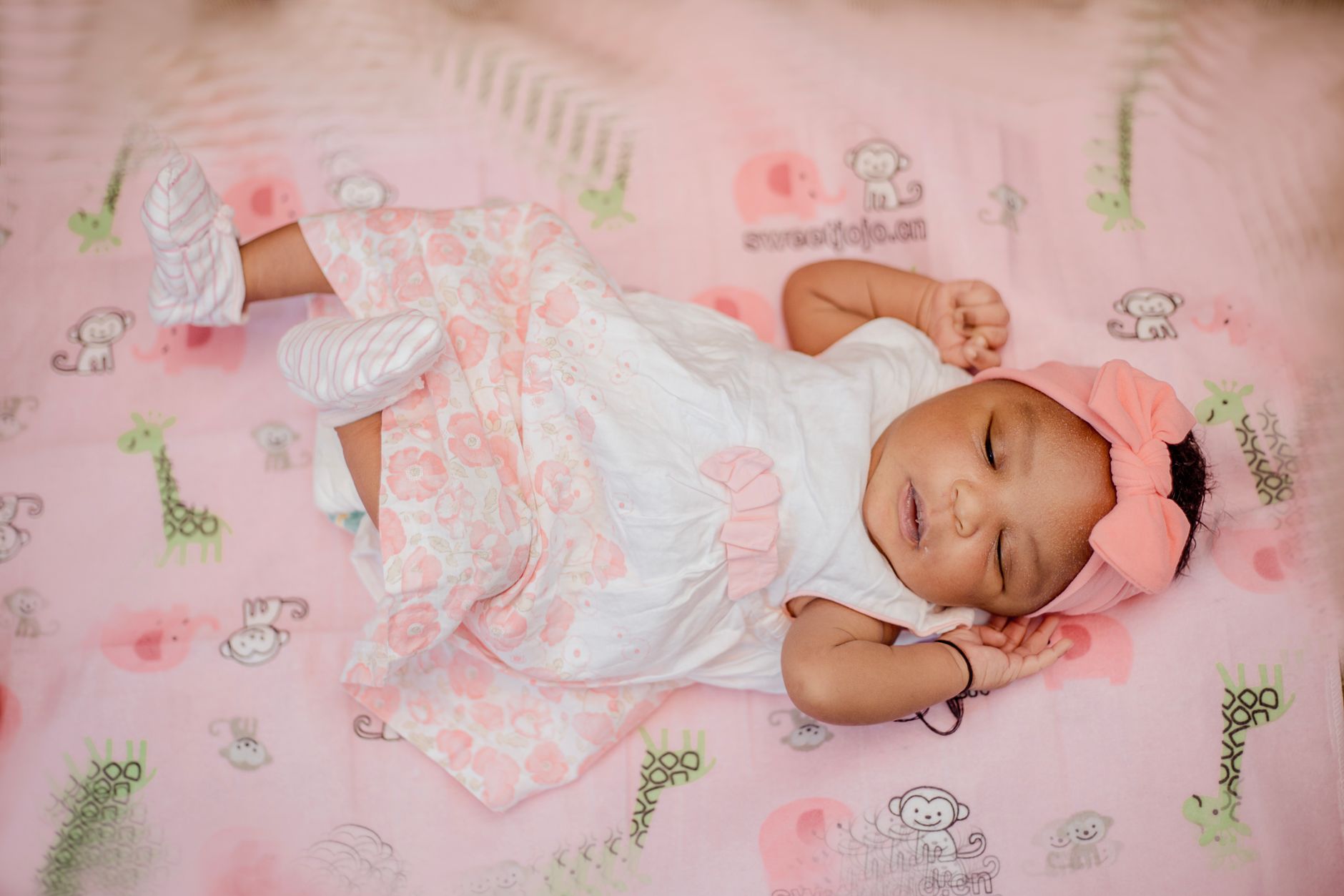 Ilustrasi: A cute baby girl peacefully sleeping in a pink-themed crib setting.