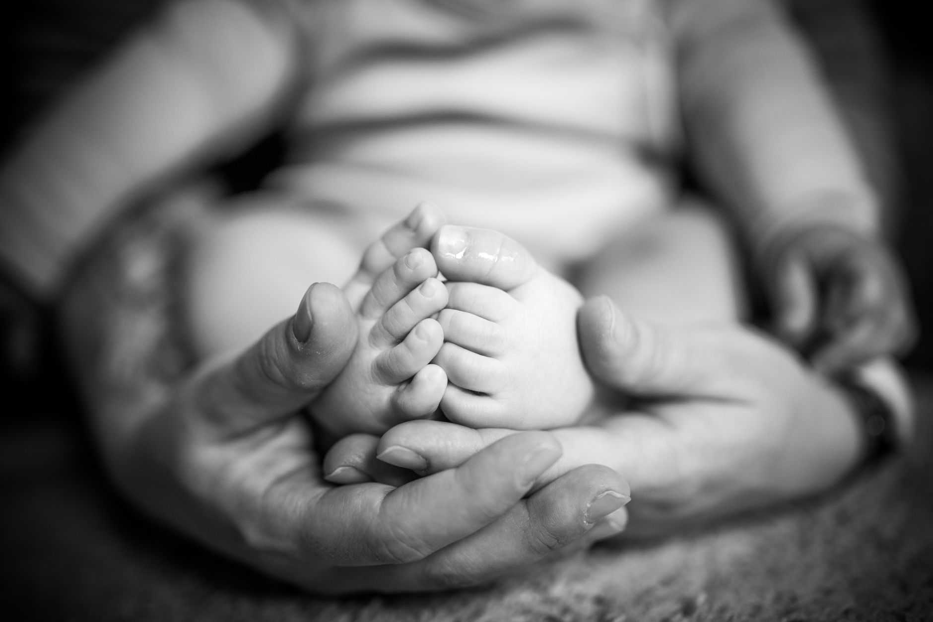 Ilustrasi: Close-up of a parent's hands gently holding the feet of a newborn baby, capturing a tender moment.