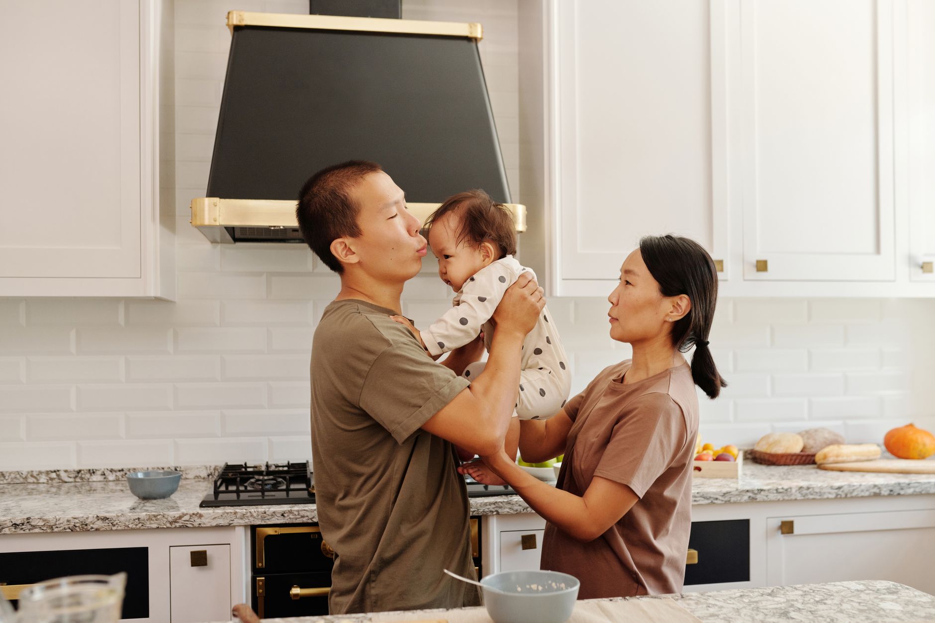 Ilustrasi: Asian family enjoying bonding time in their modern kitchen. Parents holding baby with joy.