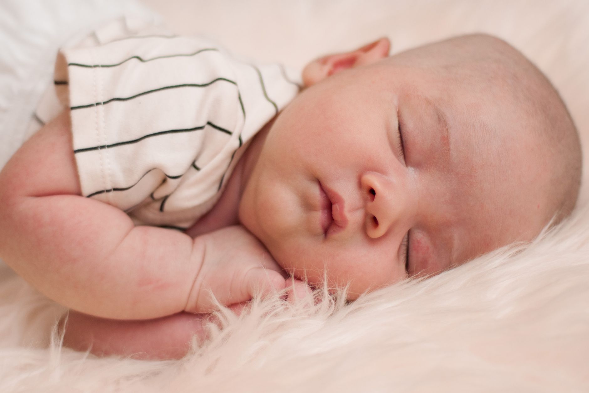 Ilustrasi: Adorable baby sleeping peacefully on a cozy white blanket, close-up portrait.